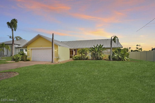 view of front facade with fence, a yard, metal roof, concrete driveway, and a garage