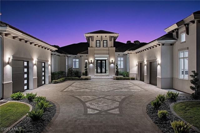 exterior space with decorative driveway, french doors, an attached garage, and stucco siding