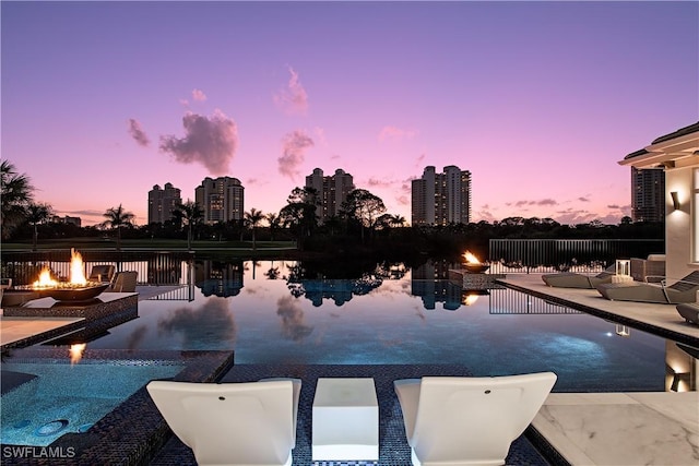 pool at dusk with a view of city, a patio, and an outdoor fire pit