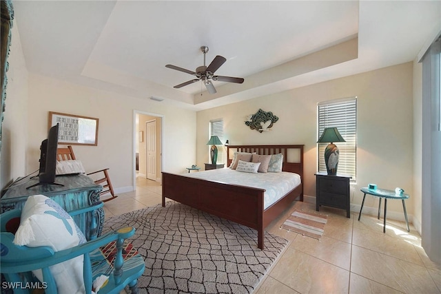 bedroom with a raised ceiling, visible vents, baseboards, and light tile patterned flooring