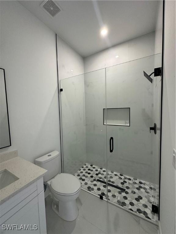 bathroom featuring toilet, a stall shower, vanity, and visible vents