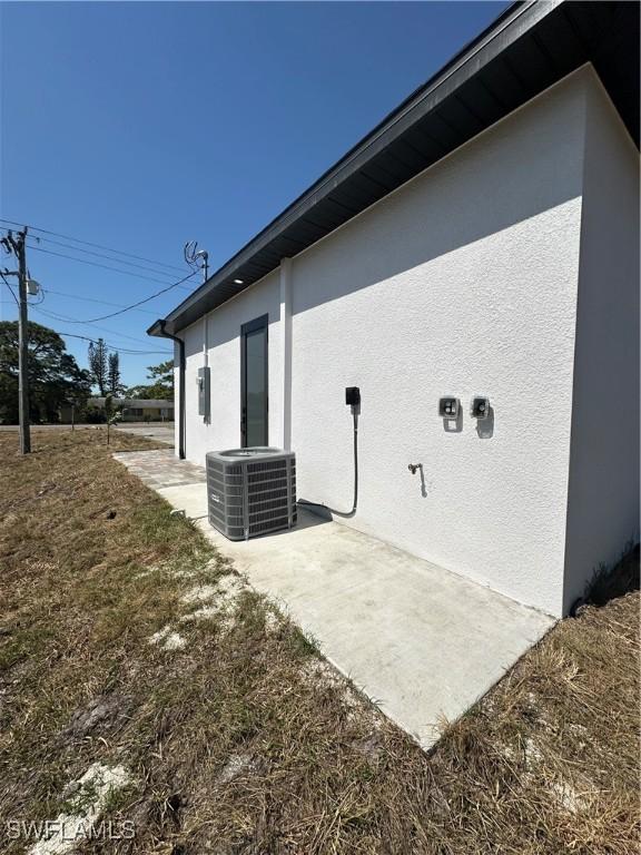 view of side of home with stucco siding and central AC unit