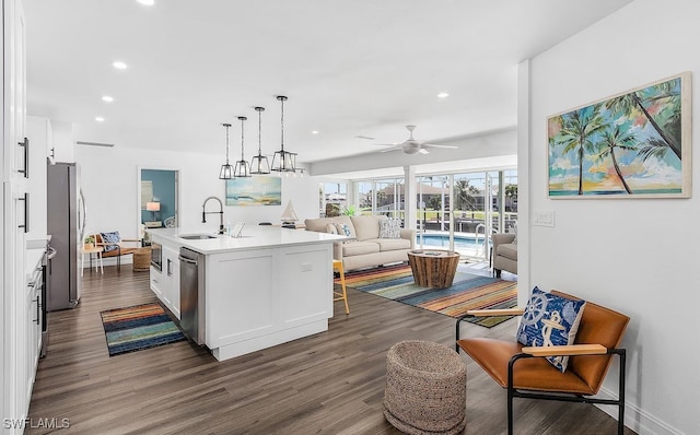 kitchen featuring white cabinets, dark wood-style floors, open floor plan, stainless steel appliances, and a sink