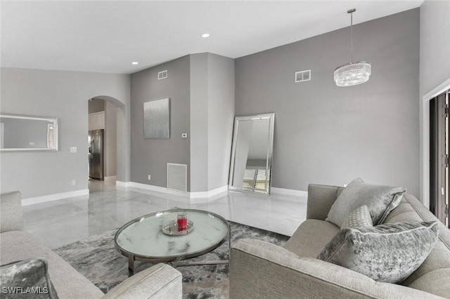 living room featuring arched walkways, visible vents, and baseboards