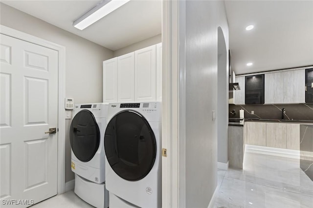 washroom featuring recessed lighting, cabinet space, washer and clothes dryer, and baseboards