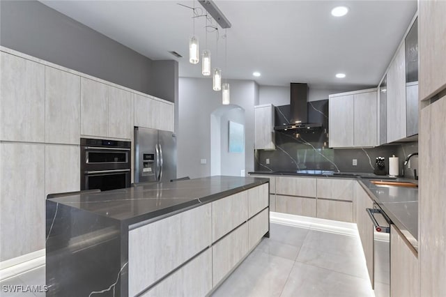 kitchen featuring stainless steel appliances, tasteful backsplash, dark stone countertops, modern cabinets, and wall chimney exhaust hood