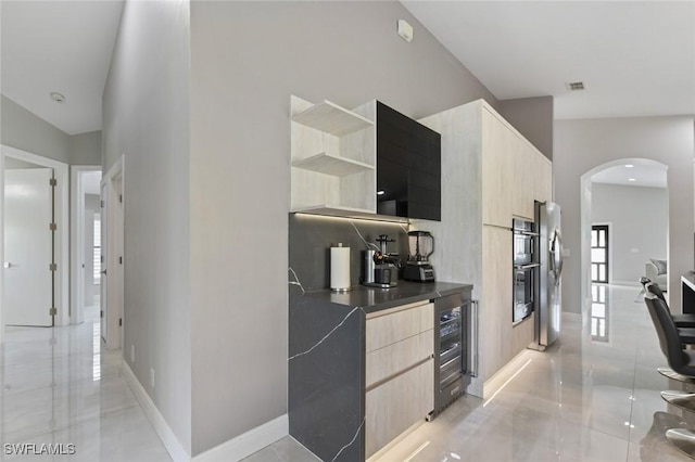 kitchen with appliances with stainless steel finishes, arched walkways, beverage cooler, and modern cabinets