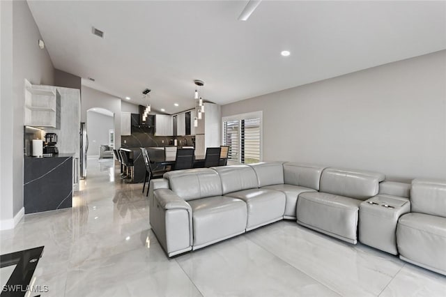 living area with arched walkways, recessed lighting, visible vents, baseboards, and marble finish floor