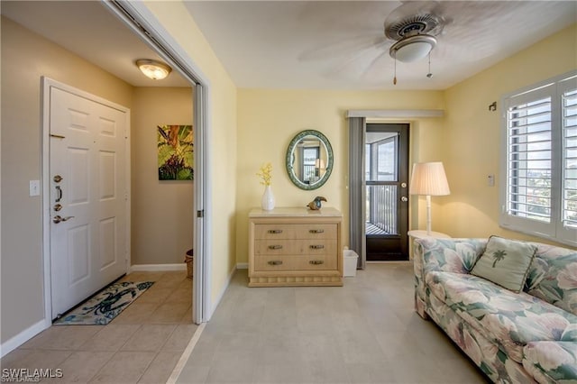 foyer with a healthy amount of sunlight, ceiling fan, and baseboards