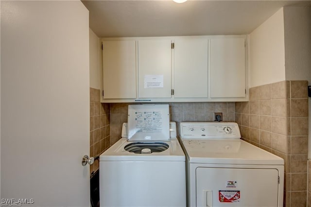 laundry room featuring cabinet space, tile walls, and washing machine and clothes dryer