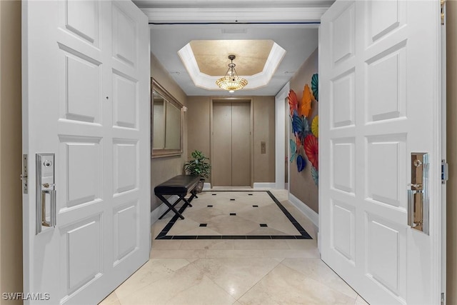 foyer entrance featuring a raised ceiling, elevator, and baseboards