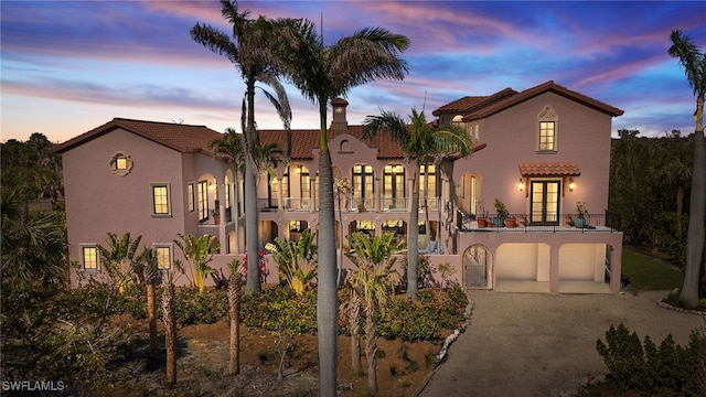 mediterranean / spanish-style house with a tiled roof, french doors, a balcony, and stucco siding