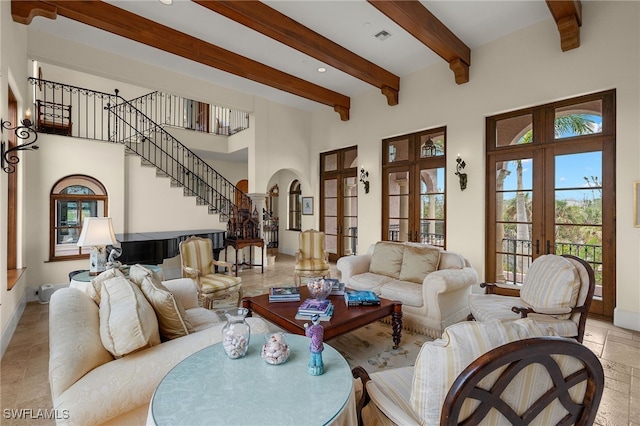 living area featuring arched walkways, a towering ceiling, stairway, french doors, and beam ceiling