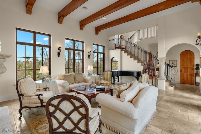 living area with arched walkways, stone tile floors, stairway, a towering ceiling, and baseboards