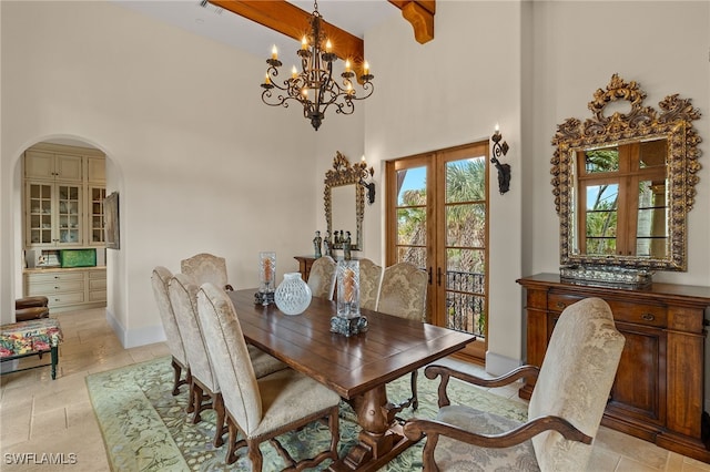 dining space featuring arched walkways, french doors, a high ceiling, a chandelier, and baseboards