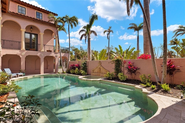 view of pool featuring fence and a pool with connected hot tub