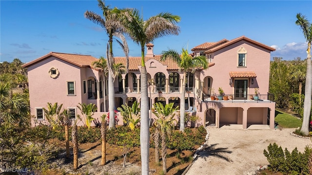 mediterranean / spanish home with driveway, a tile roof, and stucco siding