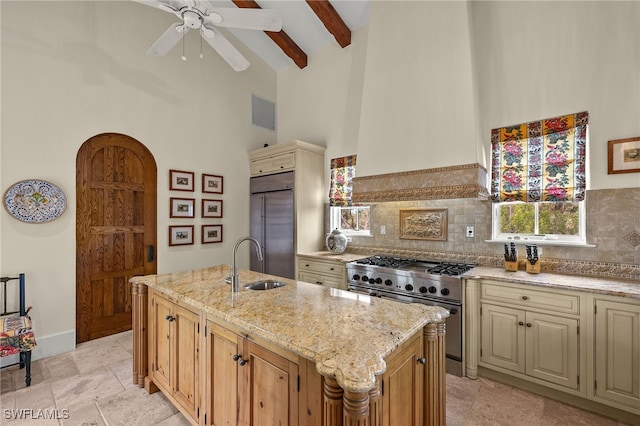 kitchen with high vaulted ceiling, light stone counters, a sink, high quality appliances, and an island with sink