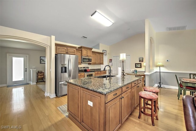 kitchen featuring arched walkways, visible vents, appliances with stainless steel finishes, a sink, and a kitchen breakfast bar