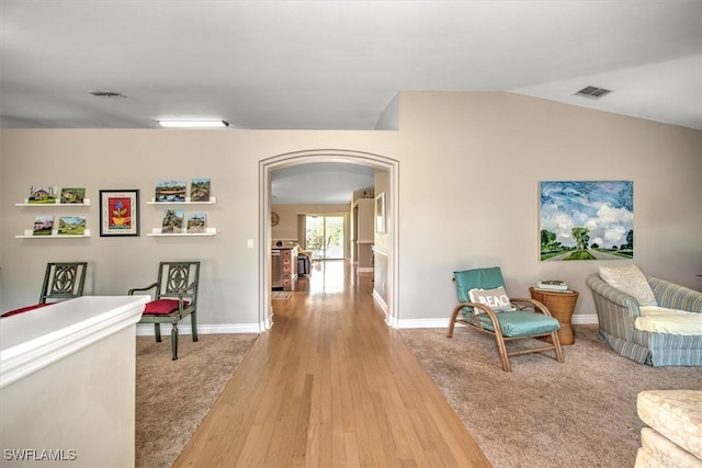 sitting room featuring arched walkways, wood finished floors, lofted ceiling, and visible vents