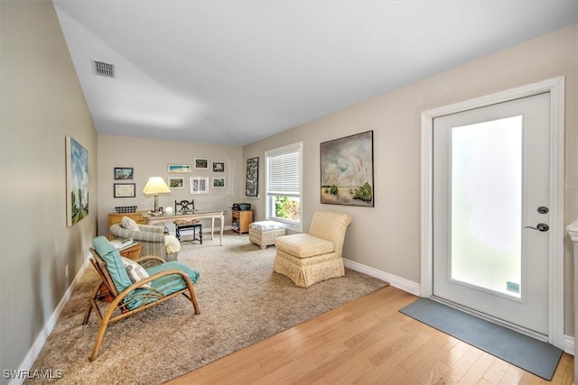 living area with visible vents, baseboards, and wood finished floors