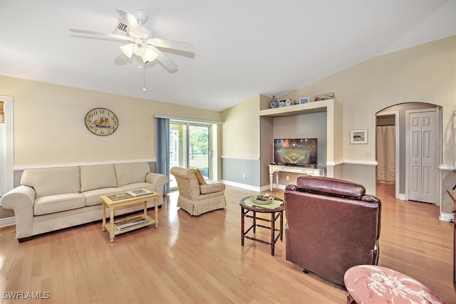 living room with arched walkways, light wood finished floors, lofted ceiling, a ceiling fan, and baseboards