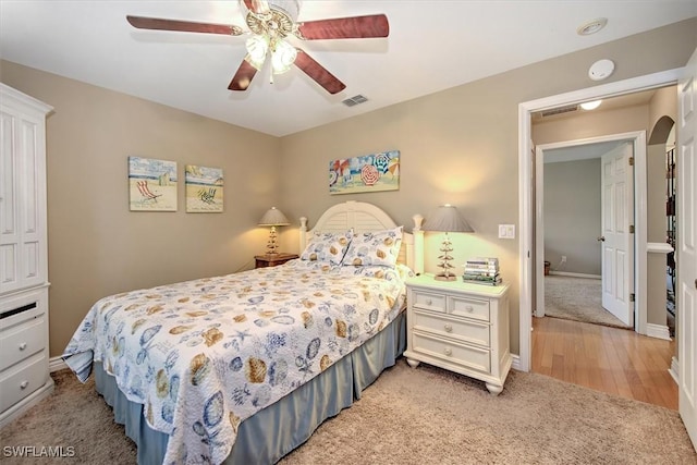 bedroom with baseboards, visible vents, arched walkways, a ceiling fan, and light colored carpet