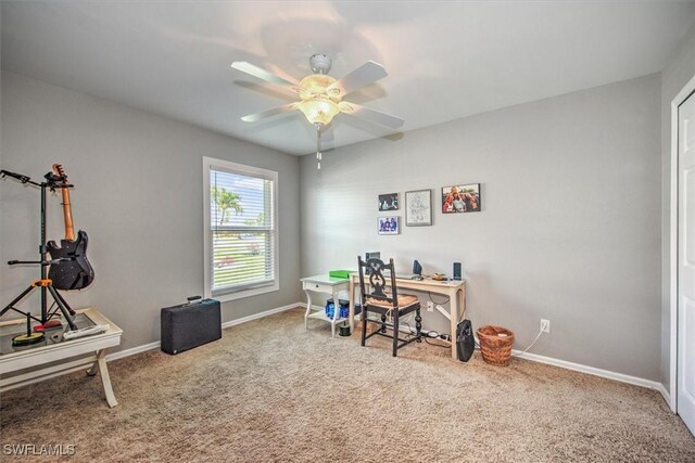 carpeted office space featuring ceiling fan and baseboards