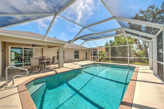 outdoor pool featuring glass enclosure, a patio, and ceiling fan