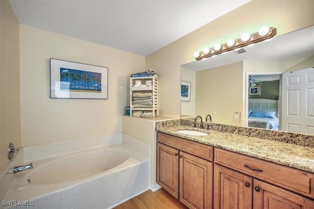 ensuite bathroom with visible vents, wood finished floors, ensuite bathroom, vanity, and a bath