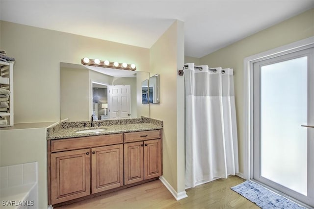 full bathroom featuring a shower with shower curtain, vanity, wood finished floors, baseboards, and a bath