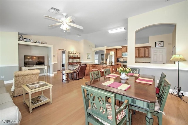 dining area featuring arched walkways, ceiling fan, visible vents, vaulted ceiling, and light wood finished floors