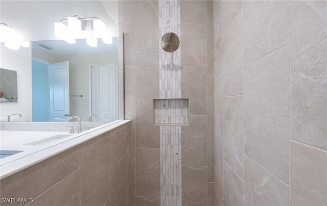 full bath featuring visible vents, a tile shower, and a sink