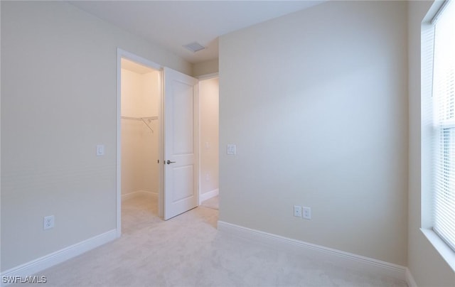 unfurnished bedroom with a spacious closet, multiple windows, a closet, and baseboards