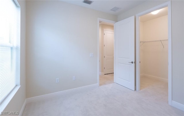 unfurnished bedroom featuring a spacious closet, visible vents, and baseboards