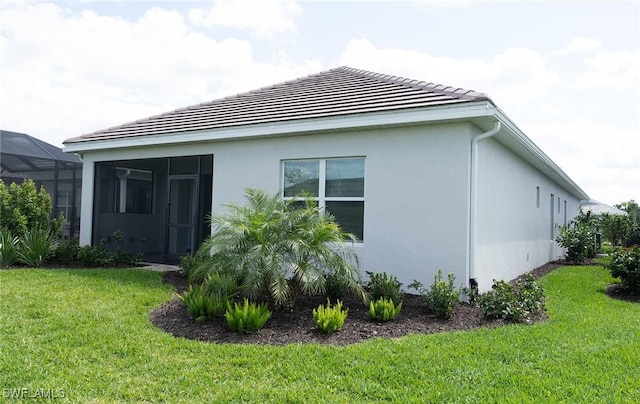 view of side of property featuring stucco siding, a tiled roof, and a yard