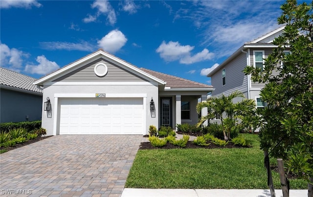 single story home featuring an attached garage, a tiled roof, decorative driveway, stucco siding, and a front yard