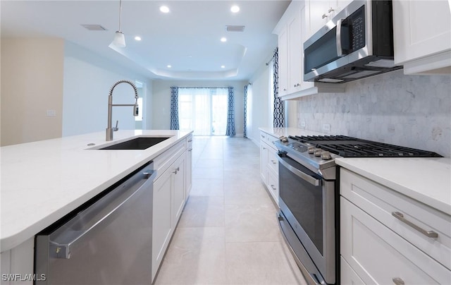 kitchen with a sink, visible vents, light countertops, appliances with stainless steel finishes, and decorative backsplash