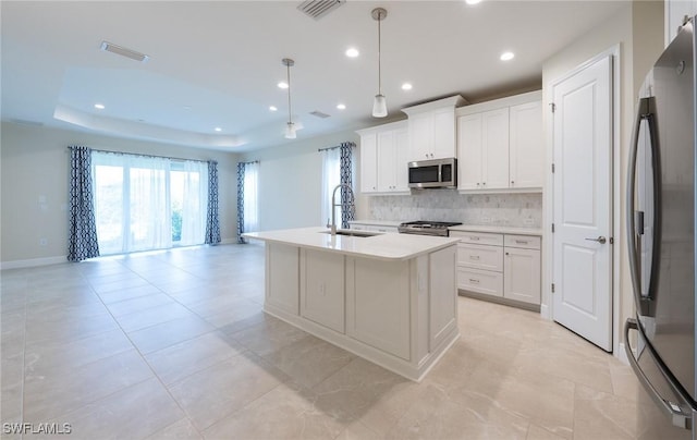 kitchen featuring stainless steel appliances, a sink, visible vents, backsplash, and a raised ceiling