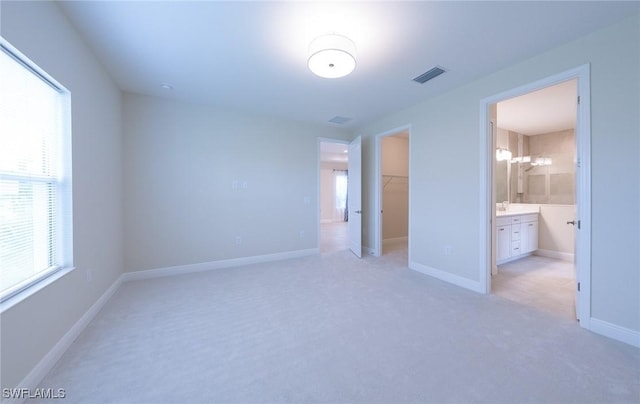 unfurnished bedroom featuring light colored carpet, visible vents, baseboards, a spacious closet, and a closet