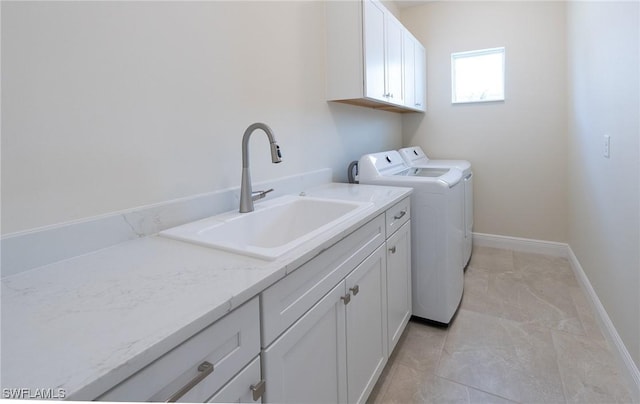 clothes washing area with a sink, cabinet space, baseboards, and washer and dryer