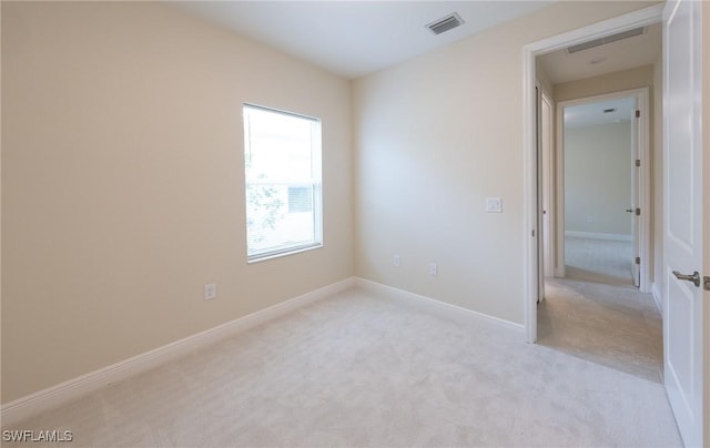 spare room with visible vents, light carpet, and baseboards