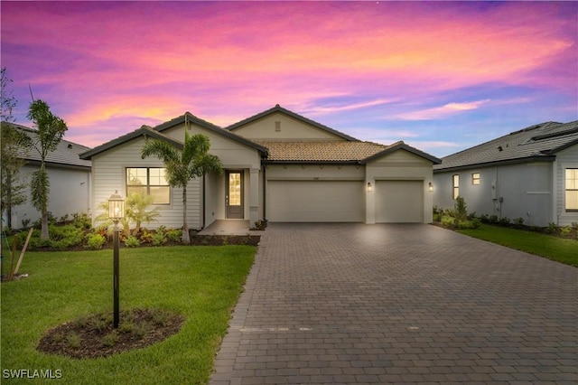 ranch-style home with a garage, a lawn, a tiled roof, decorative driveway, and stucco siding