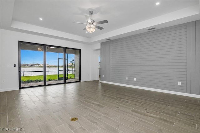 spare room with a tray ceiling, wood finish floors, and visible vents