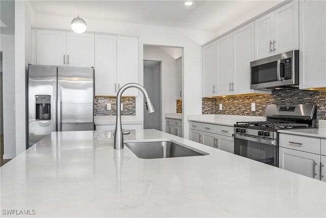 kitchen featuring stainless steel appliances, a sink, white cabinets, light countertops, and tasteful backsplash