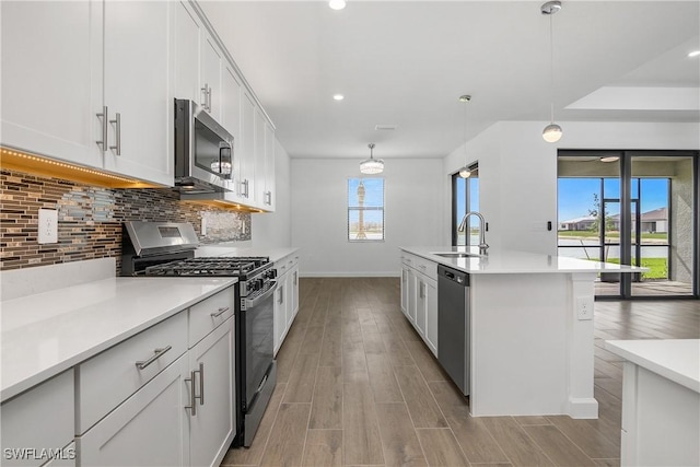 kitchen with light wood-type flooring, appliances with stainless steel finishes, decorative backsplash, and a sink