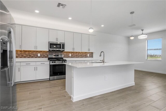 kitchen with appliances with stainless steel finishes, wood tiled floor, a sink, and tasteful backsplash