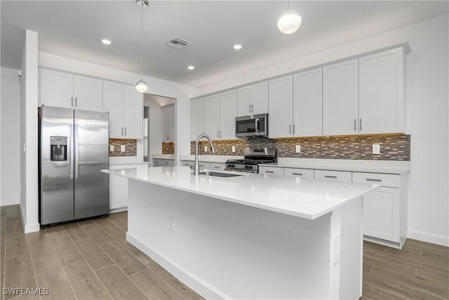 kitchen with stainless steel appliances, wood finish floors, light countertops, and visible vents