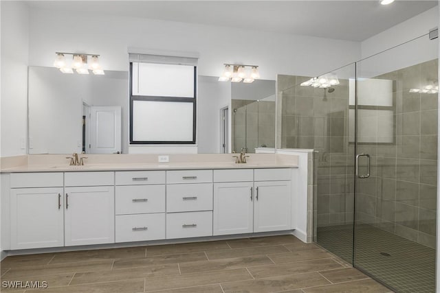 full bathroom with a stall shower, wood finish floors, a sink, and double vanity