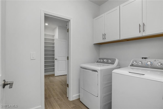 clothes washing area with wood tiled floor, cabinet space, washer and clothes dryer, and baseboards